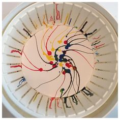 a white plate with colorful paint splattered all over the rim and inside it