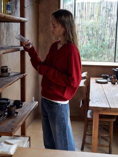 a woman standing in front of a wooden shelf filled with pots and pans