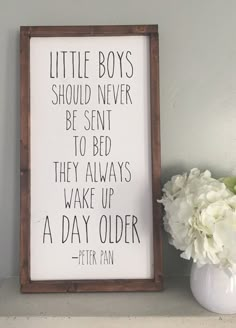 there is a vase with flowers next to a sign that says, little boys should never be sent to bed they always wake up a day older