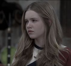 a young woman with long hair wearing a black and white top looking off to the side