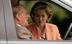 an older man and woman sitting in the driver's seat of a car looking at each other