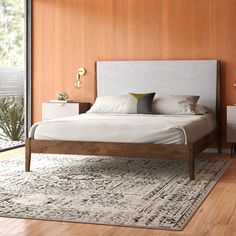 a large bed sitting on top of a wooden floor next to a tall glass window