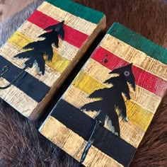 two pieces of art made out of wood and painted with black silhouettes on them