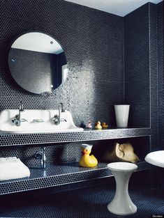 a bathroom with black and white tile, sink, mirror and yellow rubber ducky toy