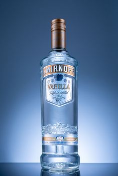 a bottle of vodka on a table with a blue backround behind the bottle