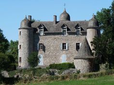 an old stone building with two towers and windows on the top floor, surrounded by greenery