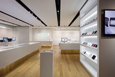 the inside of a store with wooden floors and white shelves filled with cell phones on display