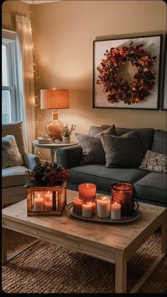 candles on a coffee table in front of a couch with a wreath hanging above it