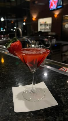 a red drink sitting on top of a table next to a strawberries garnish