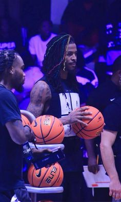 two men holding basketballs while standing next to each other in front of an audience