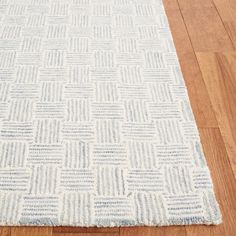 a white and blue rug sitting on top of a wooden floor next to a hard wood floor