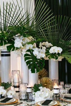 the table is set with white flowers and greenery