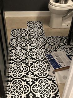 a bathroom with black and white flooring next to a toilet in the middle of it