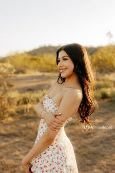 a beautiful young woman in a white dress posing for a photo with her arms around her chest