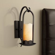 a candle is lit on the wall next to a black leather headboard and bed