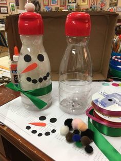 two snowman bottles sitting on top of a table next to ribbon and other items