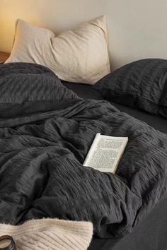 an unmade bed with a book and pair of scissors on it