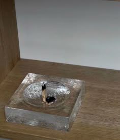 a metal object sitting on top of a wooden table next to a white wall and floor