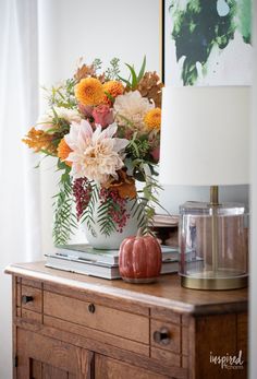 an arrangement of flowers in a vase on a dresser