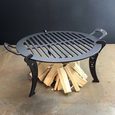 a grill sitting on top of a wooden table next to a pile of firewood