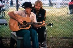 two men are sitting on a bench with guitars in their hands and one is playing the guitar