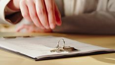 a close up of a person's hand touching a pair of wedding rings on top of a book