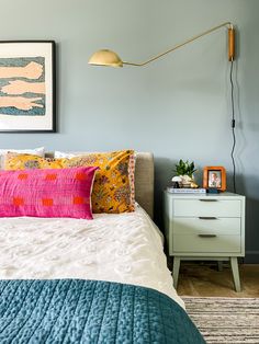 a bedroom with blue walls and white bedding has colorful pillows on the headboard