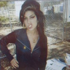 a woman with long hair standing in front of a fence