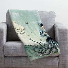 an octopus is sitting on the back of a couch with a mermaid blanket over it