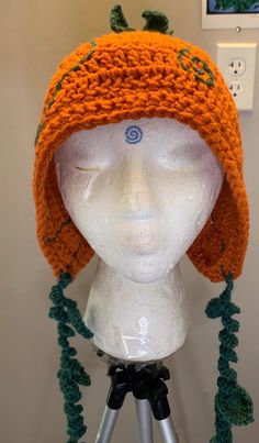 an orange crocheted hat on top of a mannequin's head