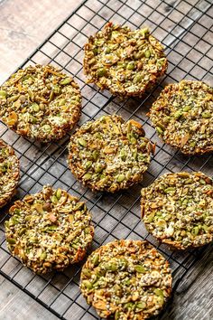 six cookies cooling on a wire rack with nuts and other things in the tray next to them