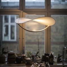 a light hanging over a kitchen counter in front of a window with potted plants