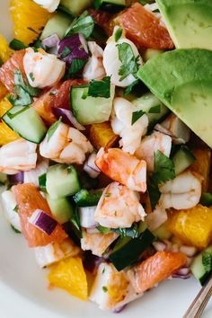 a salad with shrimp, avocado, and oranges on a white plate