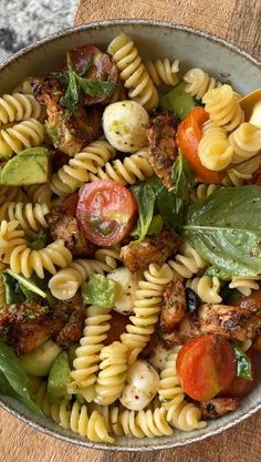 a bowl filled with pasta salad on top of a wooden table