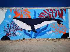 a mural painted on the side of a building depicting a humpback whale and corals