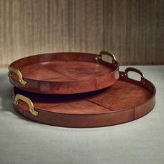 two brown leather trays with handles are sitting on a table