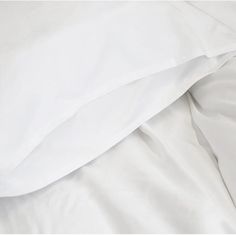 an unmade bed with white sheets and pillows