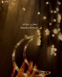 a person holding up a clear glass object with lights behind it and the words ramam muhark written in arabic