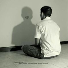 a man sitting on the floor in front of a wall with a shadow behind him