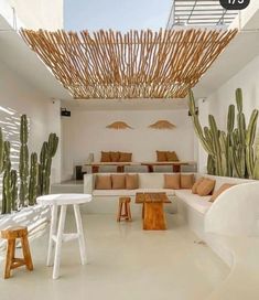 a living room filled with lots of white furniture and cactus plants on the wall next to it