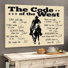 the code of the west is displayed on a wall next to a table with fruit