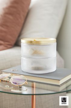 a glass table with a book and glasses on it next to a white couch in a living room