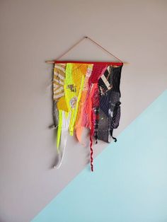 there is a wall hanging made out of different colored pieces of cloths and feathers