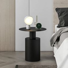 a black table with a white lamp on it next to a bed and nightstand in a bedroom