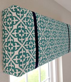 a green and white window valance hanging on the side of a wall