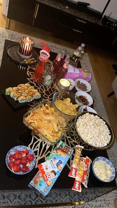 a table filled with snacks and drinks on top of a black countertop next to a candle