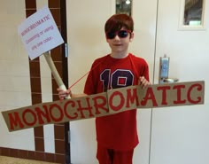 a young boy holding up a sign that says monochromatic