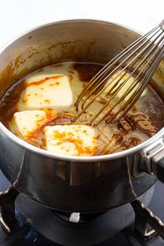 some food is being cooked in a pot on top of the stove with a whisk