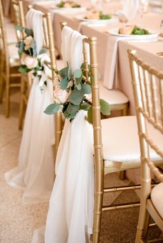 a row of gold chairs with white table cloths and flowers on each one side