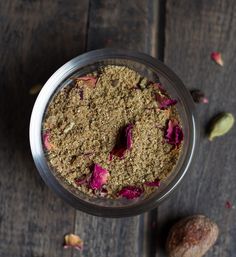 a jar filled with food sitting on top of a wooden table next to two nuts